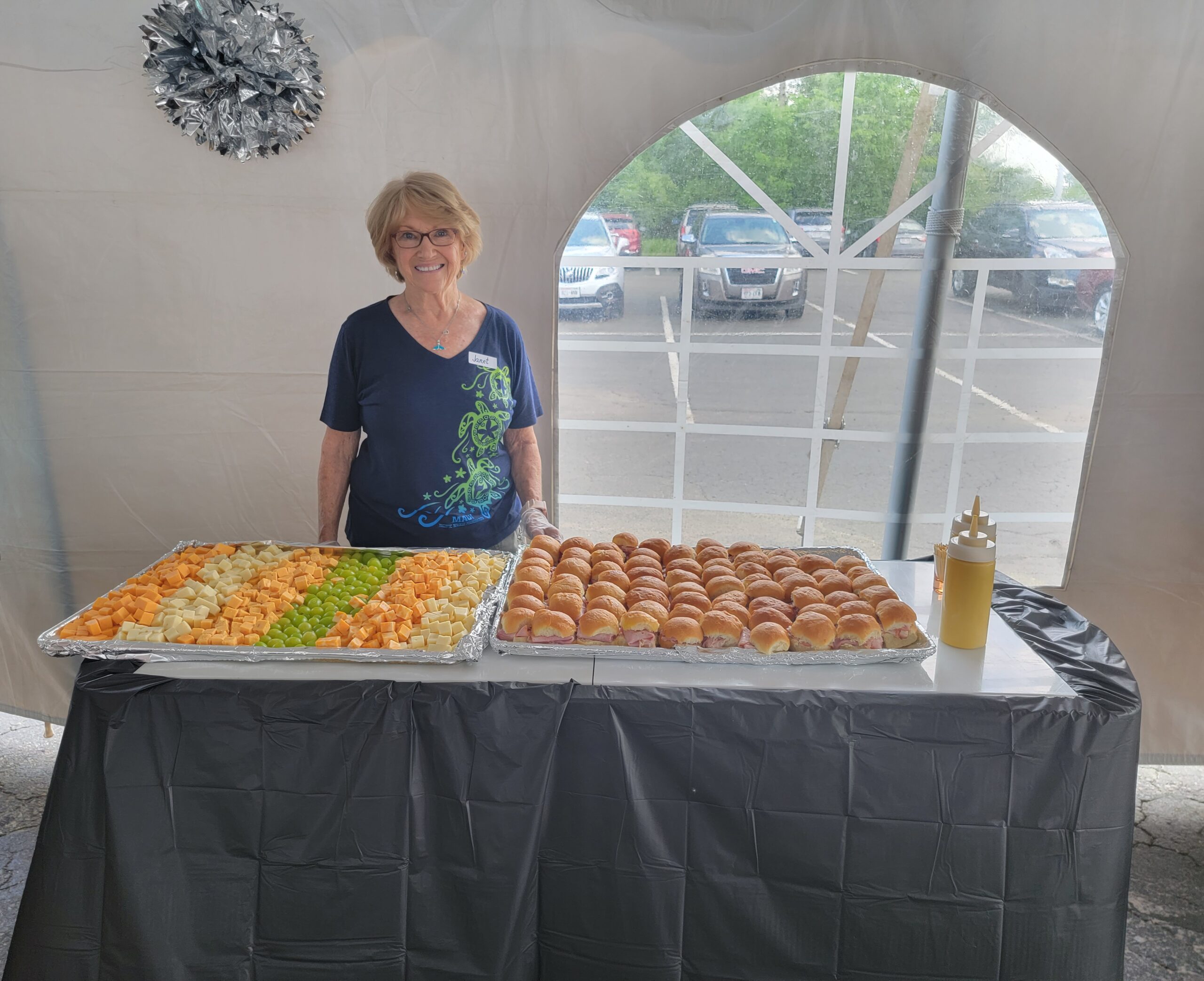 Open House volunteer offering sandwiches and cheeses.